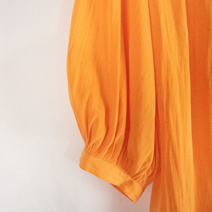 Bright orange long sleeve tunic blouse by Chicos hanging on a white hanger, showing front, back, sleeves, and fabric texture with small pinprick flaw image 2