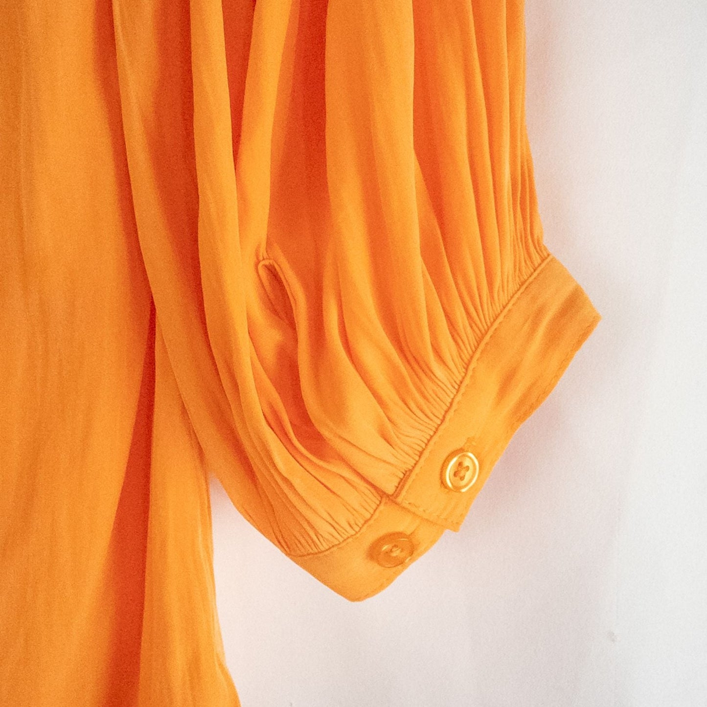 Bright orange long sleeve tunic blouse by Chicos hanging on a white hanger, showing front, back, sleeves, and fabric texture with small pinprick flaw image 6