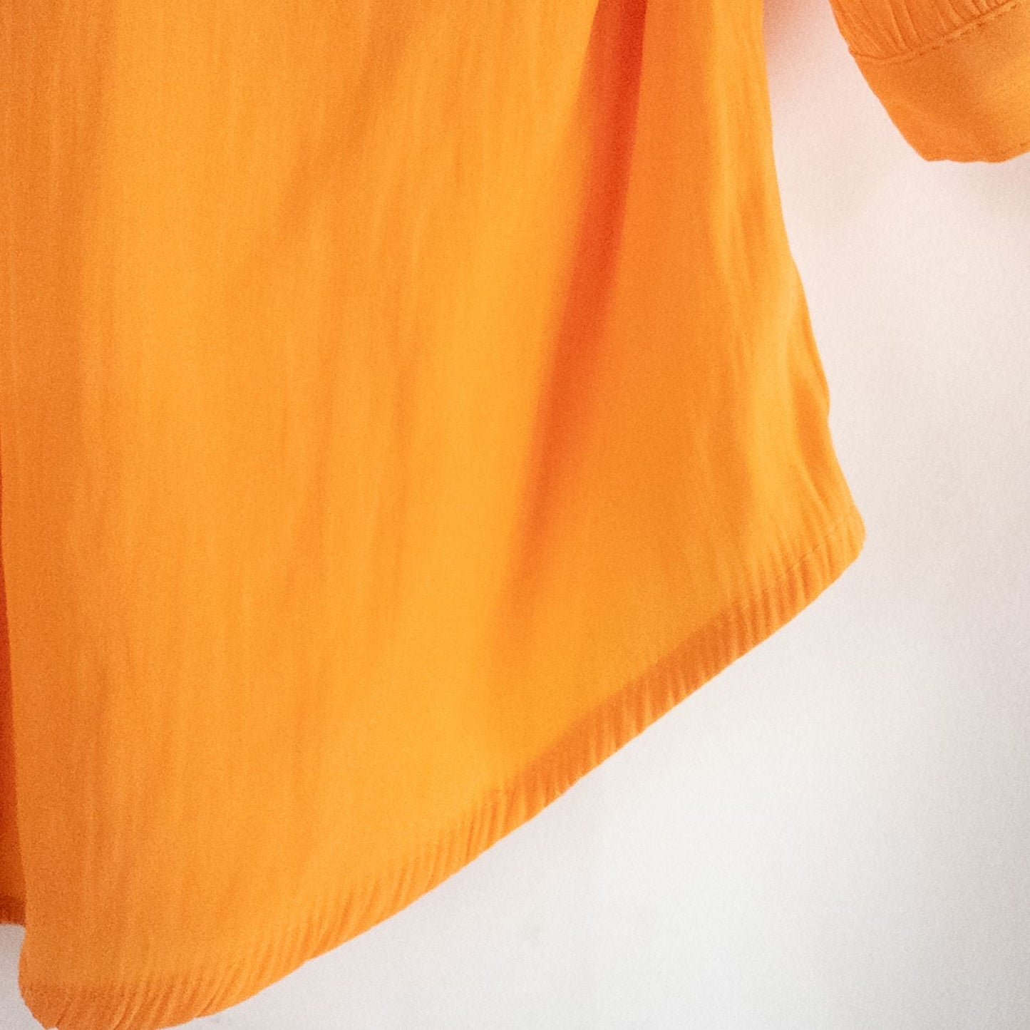 Bright orange long sleeve tunic blouse by Chicos hanging on a white hanger, showing front, back, sleeves, and fabric texture with small pinprick flaw image 4