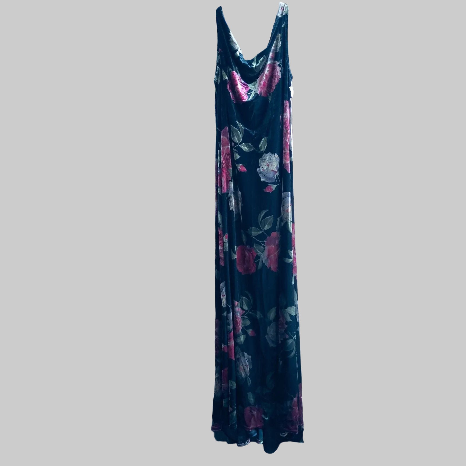 Vintage Jeffrey & Dara red rose velvet evening dress size 12 hanging in front of bookshelves showcasing black velvet fabric with red and purple rose floral pattern and cowl neckline.
