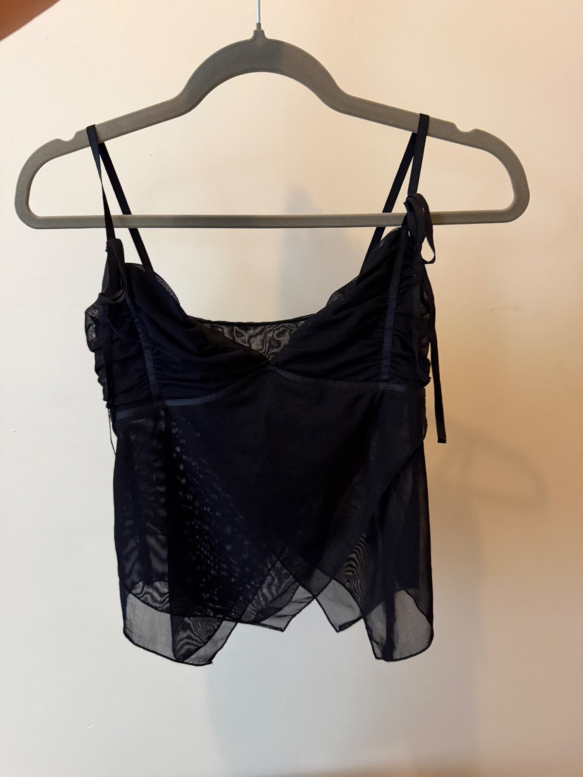 Black Shaye tank top with ruched bust and layered sheer chiffon overlay on a model and hanging on a hanger image 2