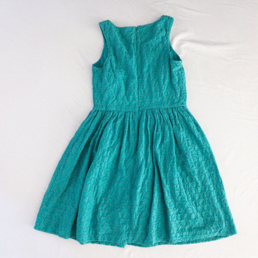 Old Navy teal green doily pattern sleeveless summer dress with gathered waist and concealed back zipper hanging on a clear hanger against a white cloth background image 6