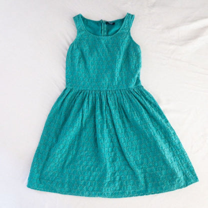 Old Navy teal green doily pattern sleeveless summer dress with gathered waist and concealed back zipper hanging on a clear hanger against a white cloth background image 12