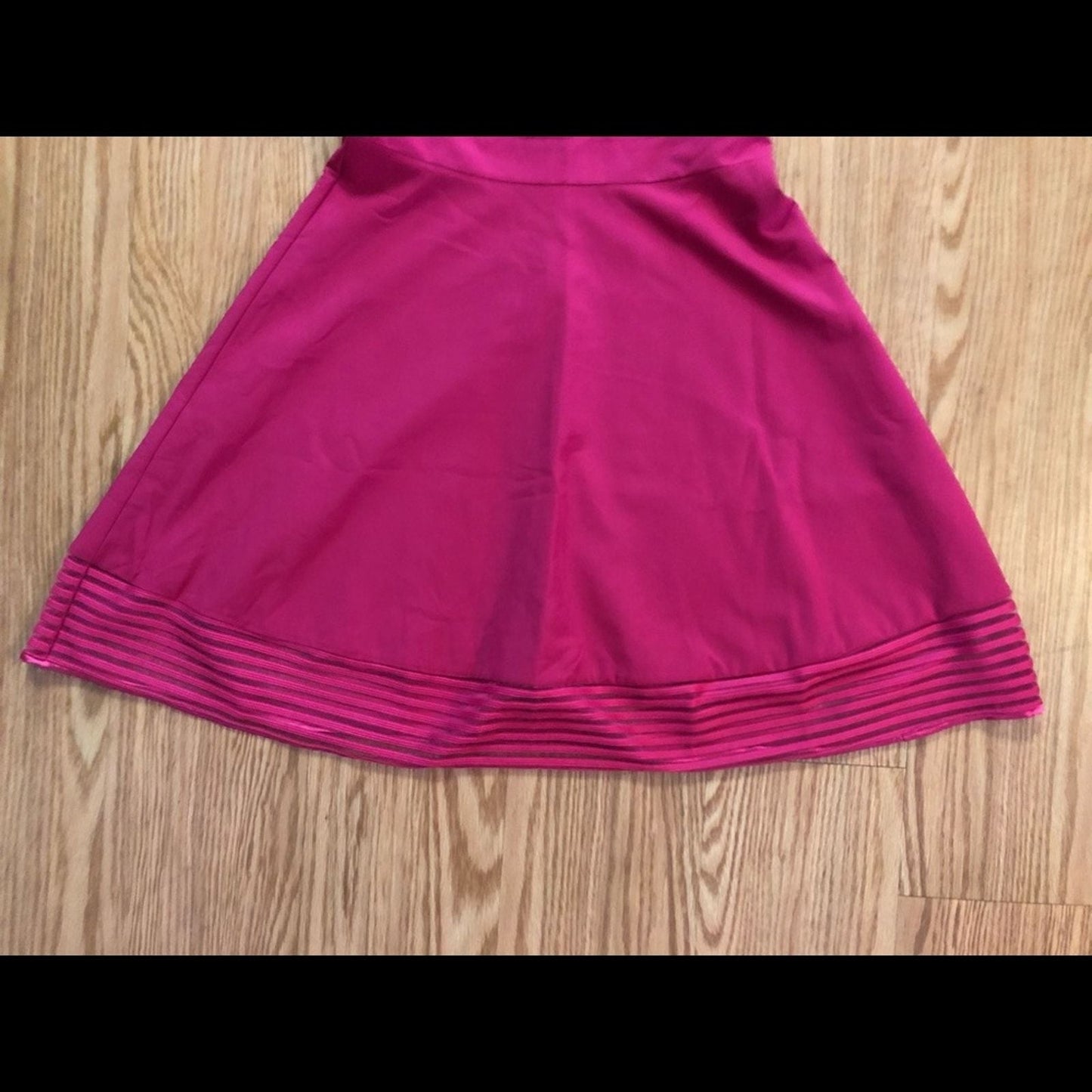 Pink sleeveless dress with sheer striped mesh panels on neckline and hem laid flat on wood floor image 4
