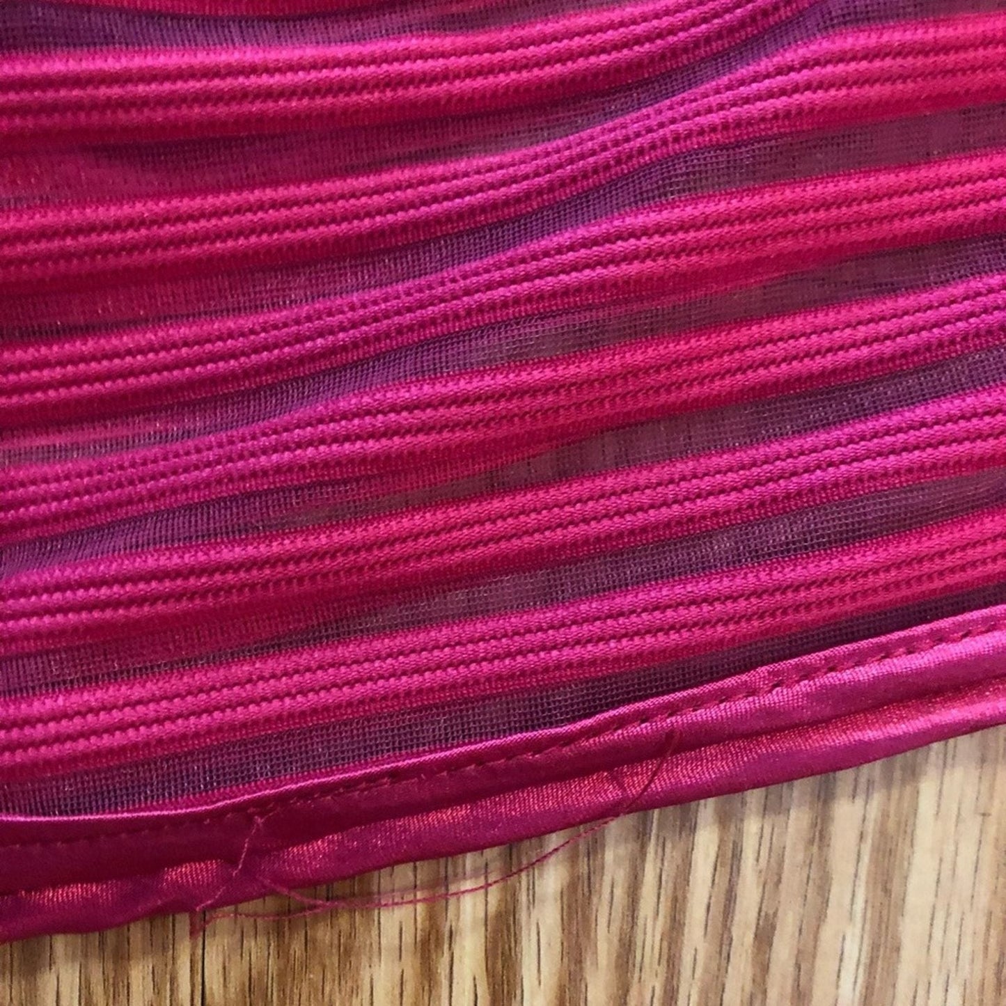 Pink sleeveless dress with sheer striped mesh panels on neckline and hem laid flat on wood floor image 8